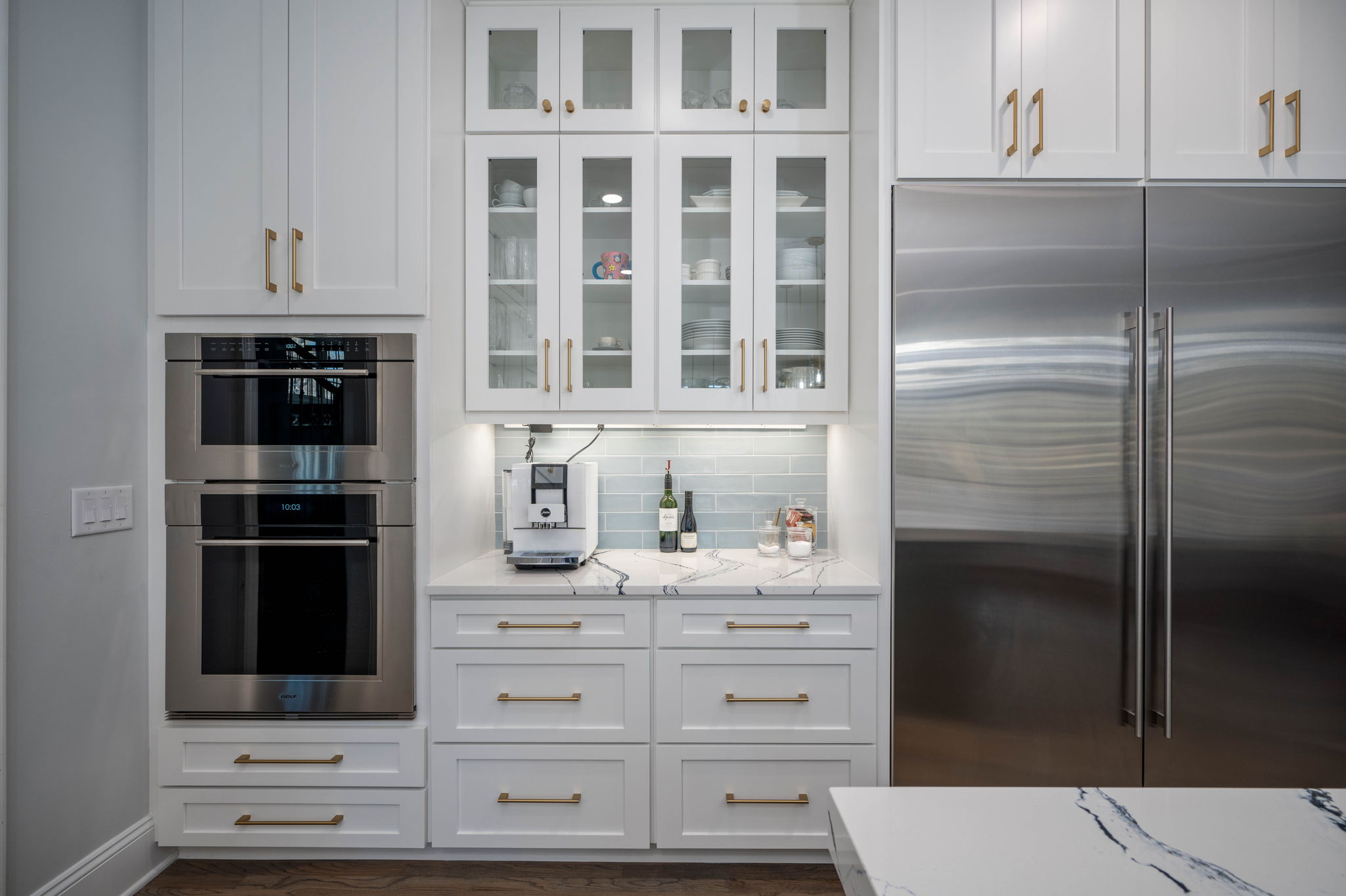 Charlotte kitchen remodel with white cabinets, gold hardware, double wall ovens and glass-front upper cabinets